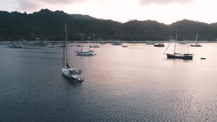 Aerial drone view of boats anchored in the bay with clear and turquoise water on the sunset. Boat and yacht in the tropical lagoon. Tropical landscape. El Nido, Palawan island, Philippines.