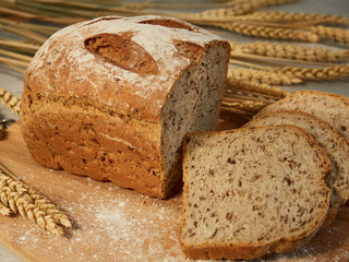 sliced grain bread, on a wooden board with ears and grains