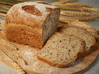 sliced grain bread, on a wooden board with ears and grains