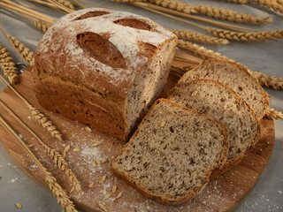 sliced grain bread, on a wooden board with ears and grains