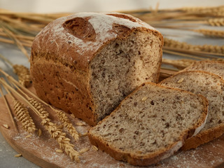 sliced grain bread, on a wooden board with ears and grains