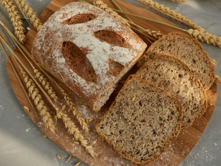 sliced grain bread, on a wooden board with ears and grains