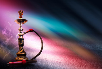 Hookah with smoke on the background of an empty scene, wet asphalt and colored neon light.