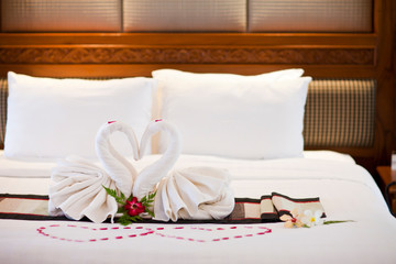Fototapeta na wymiar Alamy Two swans made of towels on bed in honeymoon suite colorful room hotel decorated for wedding or just married people
