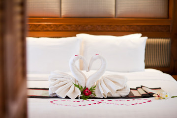 
Alamy
Two swans made of towels on bed in honeymoon suite colorful room hotel decorated for wedding or just married people