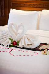 Fototapeta na wymiar Alamy Two swans made of towels on bed in honeymoon suite colorful room hotel decorated for wedding or just married people