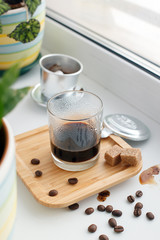 Black coffee with freshly roasted coffee beans on windowsiil in hipster coffee shop. Vietnamese style