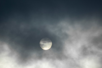 The sun is covered with dark clouds, the sun defocused in the clouds.