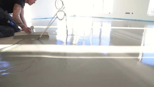 Plasterer during floor covering works with self-levelling cement mortar