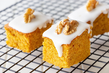 Three pieces homemade nuts carrot cake with icing cream on coolling rack. Selective focus. Close up.