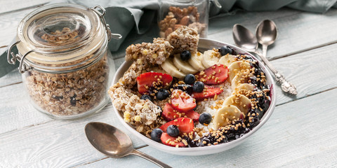 Food banner. Organic breakfast. Cottage cheese, granola, bananas, strawberries, blueberries and puffed rice. Wooden table background