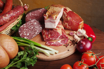 Meat products, vegetables and spices on the kitchen board.