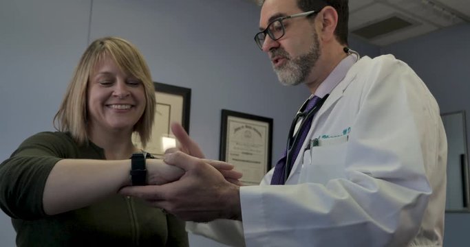 Male doctor showing a female patient how to use a smartwatch medical app