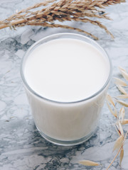 Pouring milk in the glass on blue background. Fresh milk pouring making a crown splash. Front view. Milk glass top view. Natural ingredients concept. Tasty healthy products on a table,selective focus.