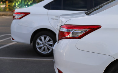 Extreme closeup of back or rear side of back car-light of white car parking in outdoor parking area in twilight evening. 