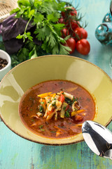 Tomato soup with fresh vegetables and sausages on blue wooden table