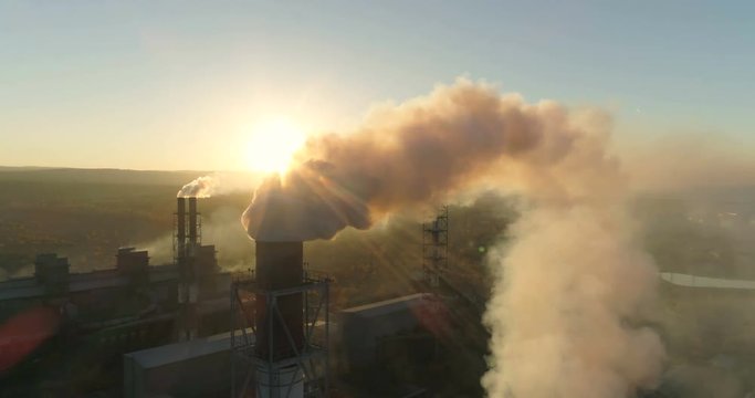 High Pollution From smoking pipis of industrial plant. Black smoke against setting sun