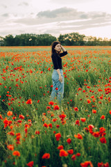 unmarried girl is standing in a field of flowers. Poppy field on the scaffold in the summer in the village.