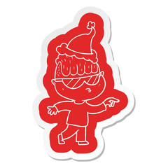 cartoon  sticker of a boy wearing sunglasses pointing wearing santa hat