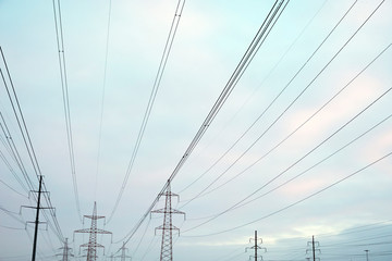 Power lines with many wires and metal supports on the open water against the sky