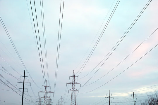 Power lines with many wires and metal supports on the open water against the sky