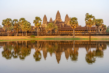 View of Angkor Wat temple on sunset in golden light with reflection in the pond