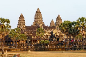 View of Angkor Wat temple's towers on sunset in golden light with reflection in the pond