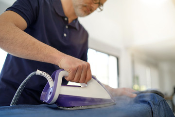 Fototapeta na wymiar Man ironing shirt in stunnig modern home