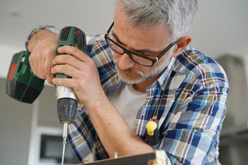 Mature man using power drill at home