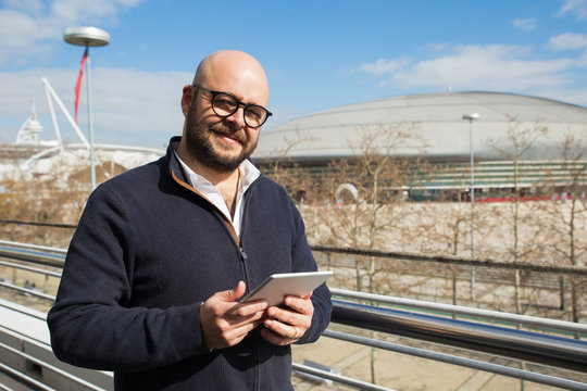 Smiling middle-aged man using tablet outdoors - Powered by Adobe
