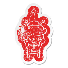 shy cartoon distressed sticker of a spaceman wearing santa hat
