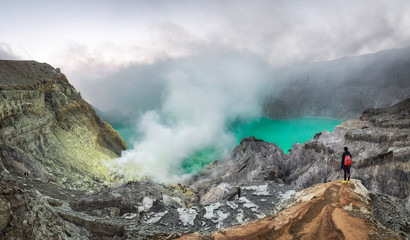 Panoramic view of the burning sulphur flames of Ijen crater and the emerald green volcanic pond...