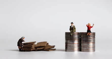 Pile of coins and miniature people. The concept of a poor senior citizen.