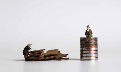 Pile of coins and miniature people. The concept of old people and economic inequality.