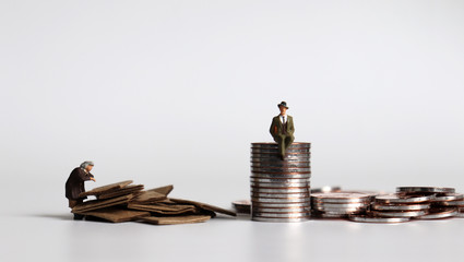 Stack of coins and miniature people. The concept of poor old age.