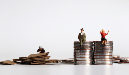 Coins with miniature people. The concept of the generation gap between rich and poor.