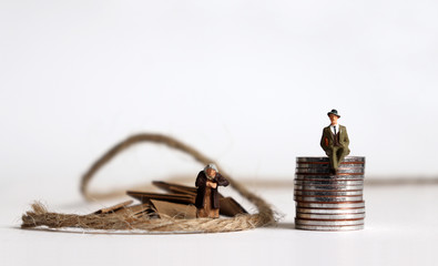 Coins with miniature people. The concept of the generation gap between rich and poor.