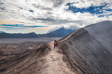 Taking a walk on the crater rim of Mount Bromo in Indonesia under the heavy clouds