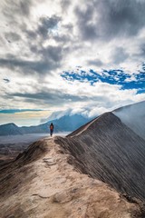 Taking a walk on the crater rim of Mount Bromo in Indonesia under the heavy clouds