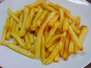 Close up of hot golden fresh crunchy french fried on a white plate, served and ready to eat at a restaurant