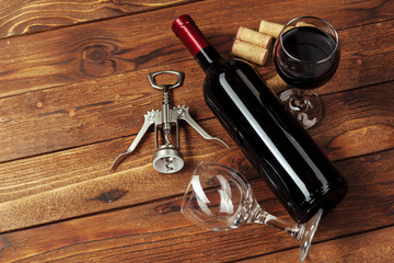 Obraz na płótnie Canvas Red wine bottle, wine glass and corkscrew on wooden table background