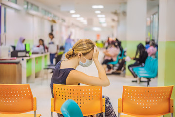 Young woman sitting in hospital waiting for a doctor's appointment. Patients In Doctors Waiting Room