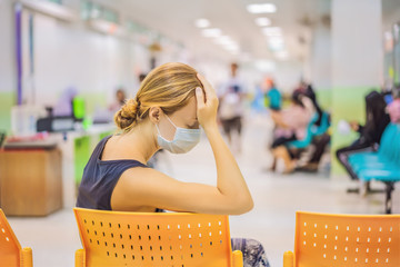 Young woman sitting in hospital waiting for a doctor's appointment. Patients In Doctors Waiting Room
