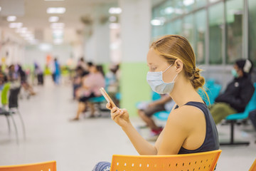 Young woman sitting in hospital waiting for a doctor's appointment. Patients In Doctors Waiting Room
