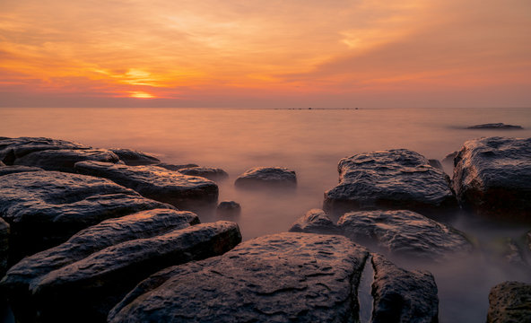 Rocks on stone beach at sunset. Beautiful beach sunset sky. Twilight sea and sky. Tropical sea at dusk. Dramatic sky and clouds. Sunset abstract background. Calm and relax life. Nature landscape.