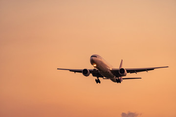 Commercial airline. Passenger plane landing at airport with beautiful sunset  sky and clouds. Arrival flight. Airplane flying for landing. Aircraft open light in the evening flight. Night flight.