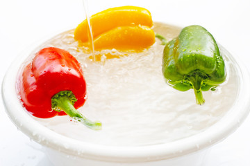 Bell pepper soaked in water. Washing fresh vegetables on white