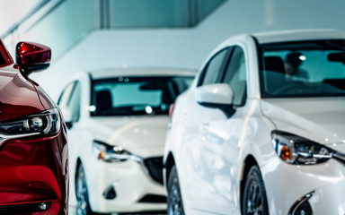 New luxury red shiny compact car parked in modern showroom. Car dealership office. Car retail shop. Electric car technology and business concept. Automobile rental concept. Automotive industry.