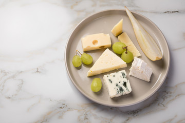 Käseteller mit Edamer, Parmesan, Blauschimmel Käse und Ziegenkäse an Birne und Trauben auf...
