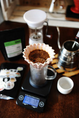 Blooming coffee in pink ceramic origami dripper with paper filter. Alternative coffee brewing. Manual grinder. Gooseneck kettle. Electronic scale